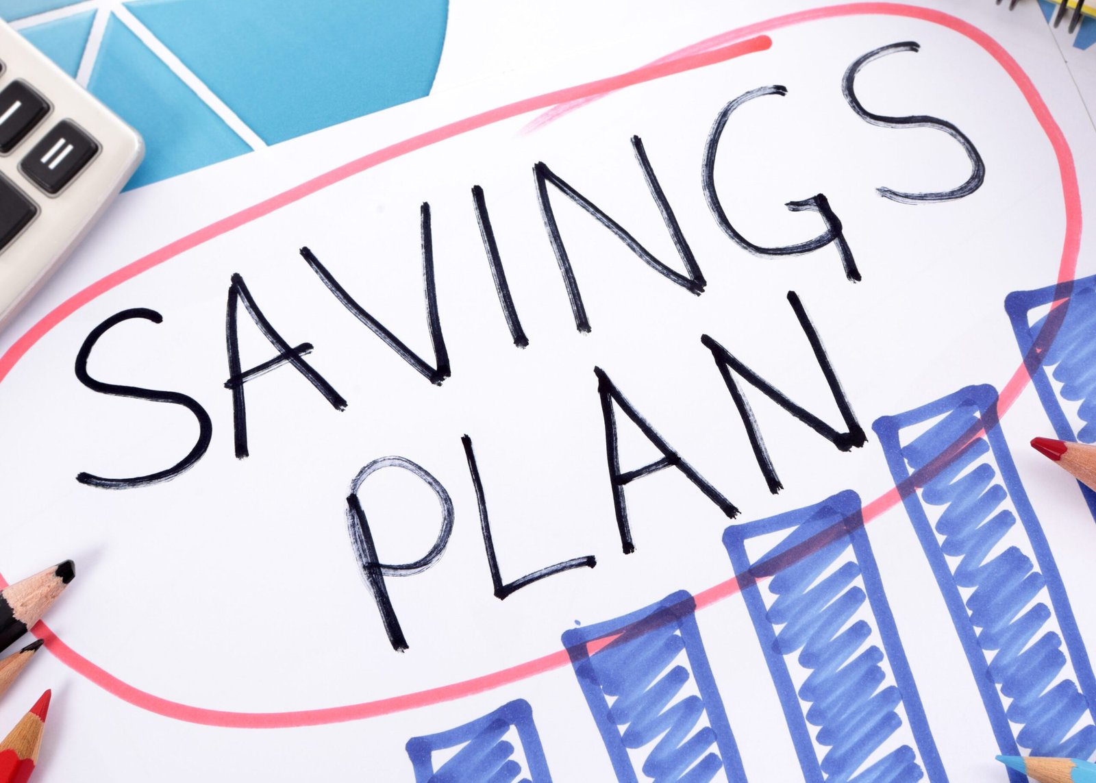 Savings plan The words Savings Plan written on a hand drawn bar chart surrounded by pencils, books and calculator.